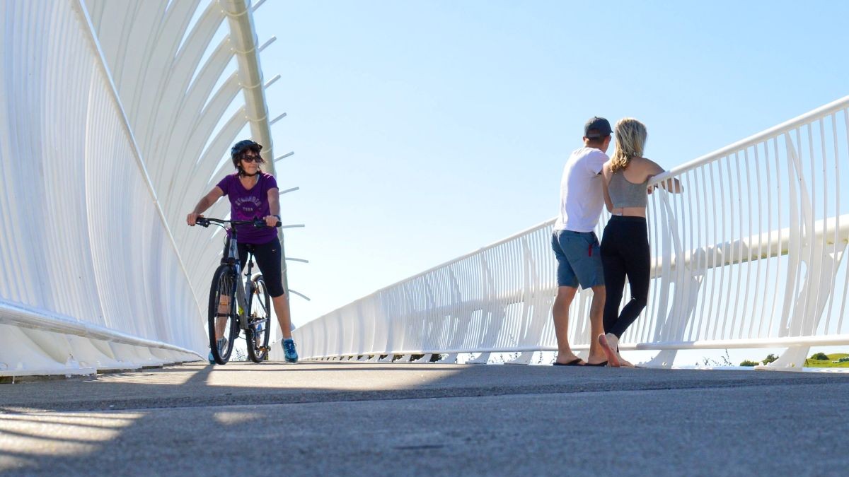 Sabina and Liam standing on Ta Rewa Rewa Bridge, resembling a whale skeleton in New Plymouth, North Island, New Zealand