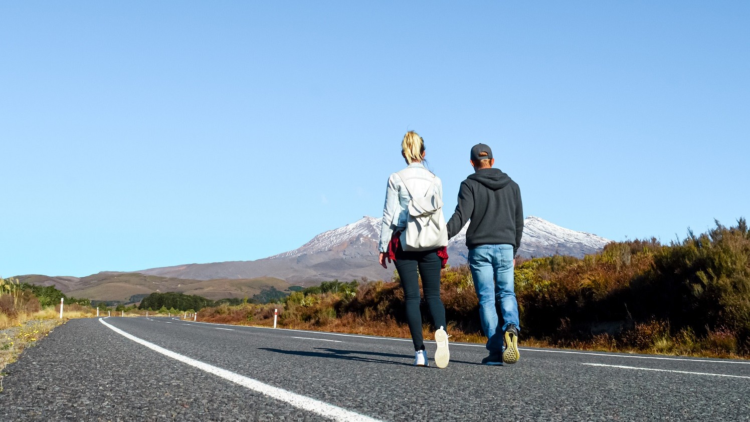 Sabina and Liam holding hands while walking on a quiet road towards Mt Ruapehu, North Island, New Zealand